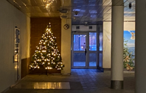Julgran som lyser upp i entrén.